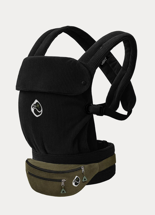 Velia Essenza Bag in Schwarz vor dunkelgrünem Hintergrund – luxuriöse Cordtasche mit ikonischem Markenlogo und eleganter Linienführung.